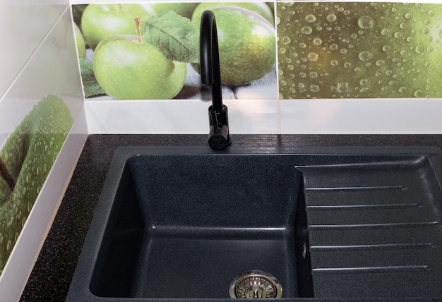 Black kitchen sink and faucet tiles on the wall Repair in the house installation of plumbing