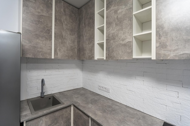 Black kitchen sink and tap water in the kitchen. the interior\
of the kitchen room of the apartment. built-in appliances. kitchen\
appliance. domestic appliances.