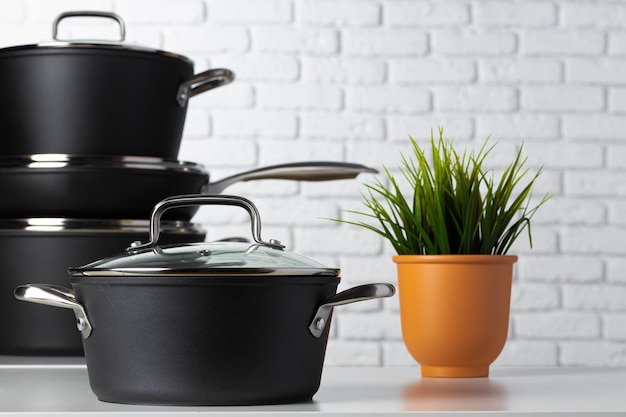 Black kitchenware on table against white brick wall