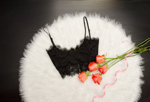 Black lace top on white fur and a bouquet of orange roses