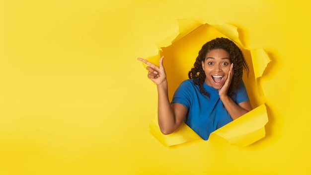 Black Lady Pointing Finger Aside At Torn Yellow Paper Background