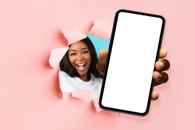 破れた紙を通して白い空のスマートフォンの画面を示す黒人女性