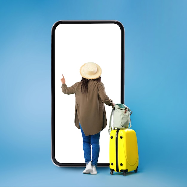 Black lady using big smartphone buying travel tickets blue background