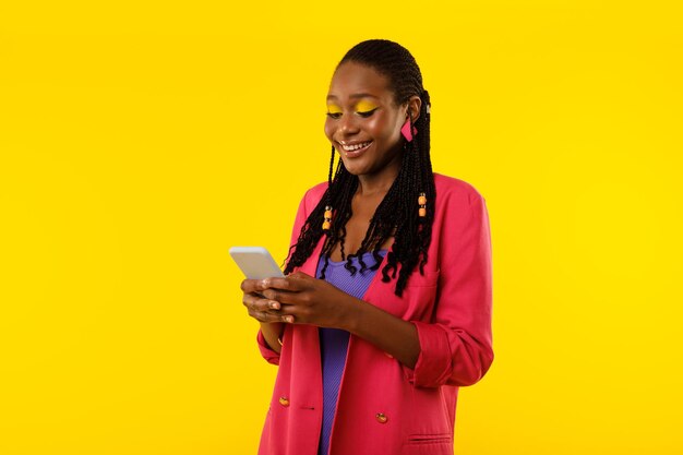 노란색 배경에 전화 미소 읽기 메시지를 사용하는 흑인 여성