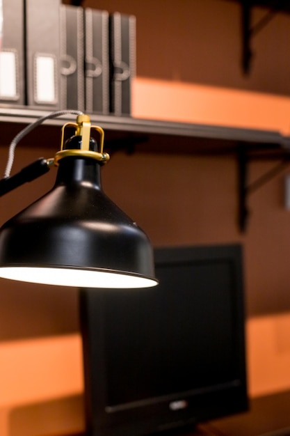 Фото Черная лампа и ноутбук стоят на столе на фоне офиса