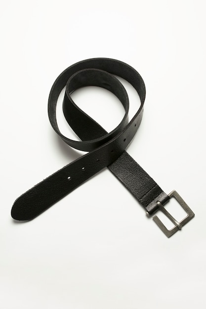 Black leather belt lying over a white background