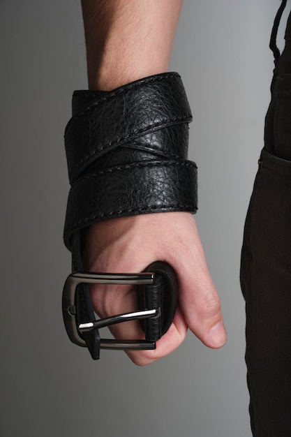 Black leather belt with metal plaque in man hand