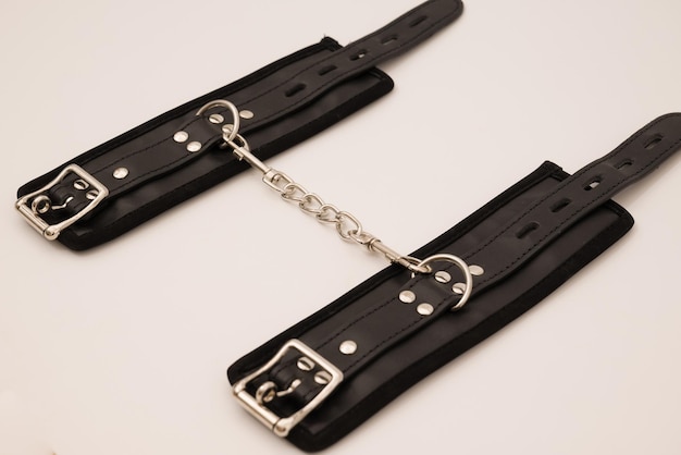 Черные кожаные наручники на белом фоне