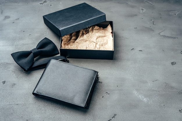 灰色の背景に黒い革の財布と蝶ネクタイ