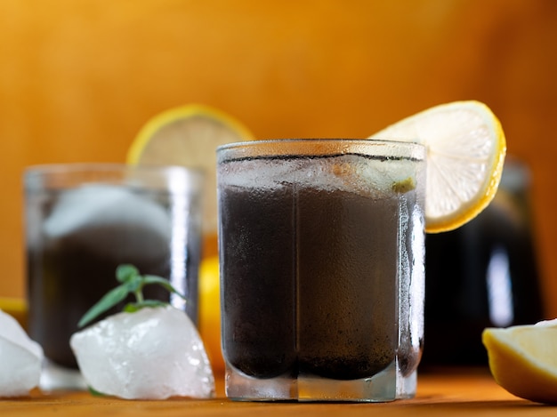 Black lemonade with mint, lemon, charcoal and ice on a wooden table