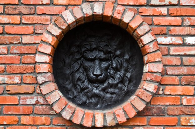 Скульптура с головой черного льва на круговой кирпичной стене в Луисвилле