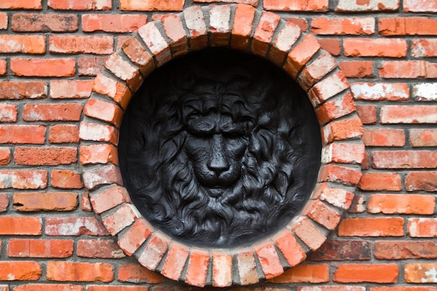 Фото Скульптура с головой черного льва на круговой кирпичной стене в луисвилле