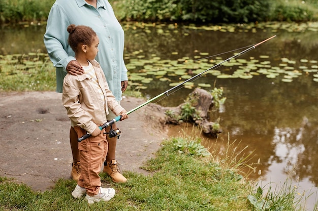 Black little girl holding fishing rod and enjoying time with mother