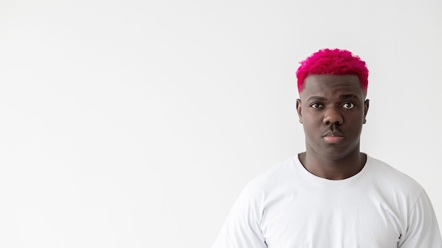 Le vite nere contano uomo serio tolleranza sociale sfondo pubblicitario attraente ragazzo africano elegante con una maglietta bianca con capelli rosa brillante isolato spazio per la copia della luce