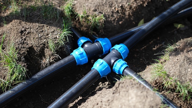 Black long pipe lies and tee adapter in dugout earth closeup