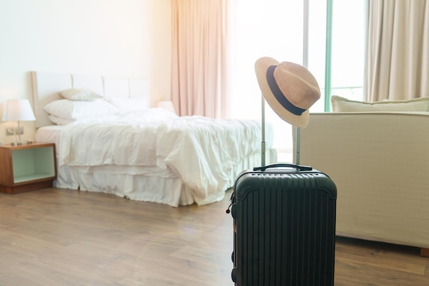 Black luggage with hat in modern hotel room after door opening
baggage for time to travel service journey trip summer holiday and
vacation concepts