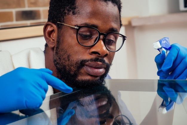 Black male cleaning a glass table at home