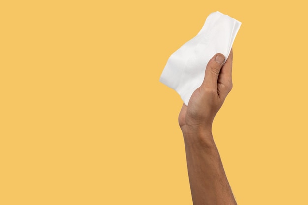 Black male hand holding a dust cleaning cloth isolated on yellow background