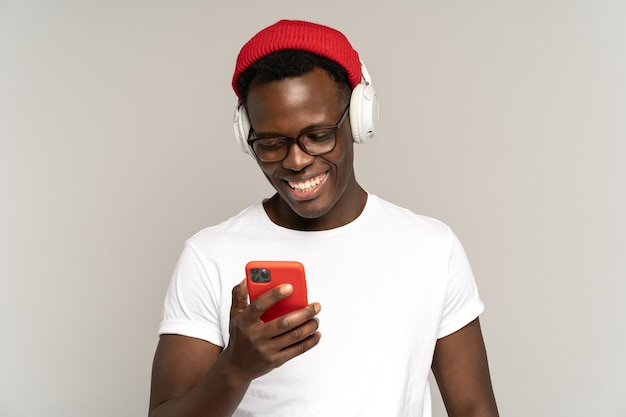 흑인 남성은 스마트폰 스튜디오 촬영에서 소셜 미디어를 사용하여 무선 헤드폰으로 음악을 듣습니다.