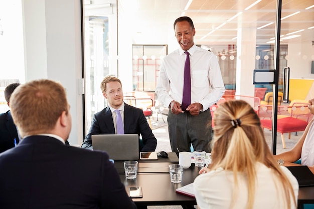 Black male manager addressing colleagues at a meeting smiles