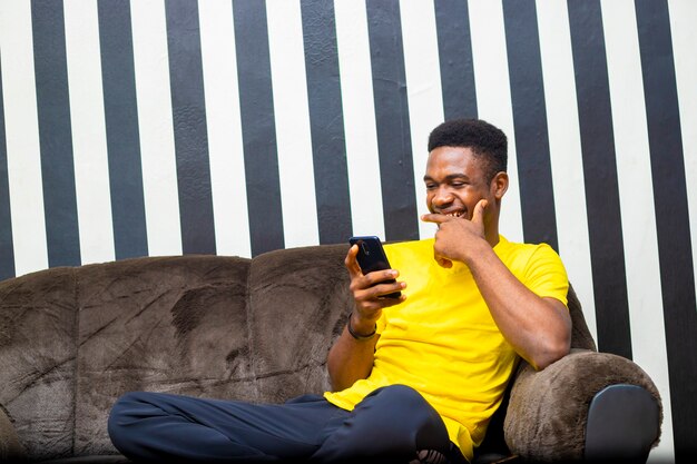 Black male millennial student chatting with his mobile phone checking internet