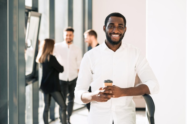 Black male office employee with cup of coffee