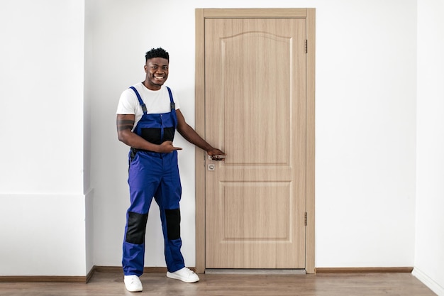 Черный работник указывает пальцем на новую входную дверь в помещении