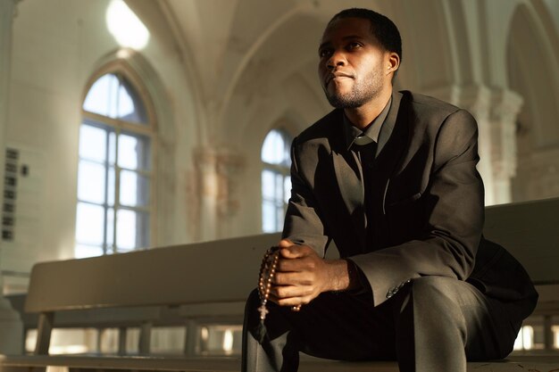 Black man as priest holding rosary in church