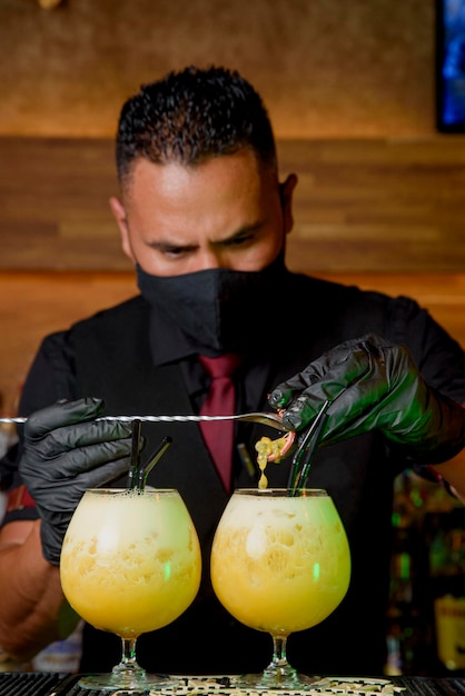 Black man bartender with mask preparing a cocktail. drinks\
concept