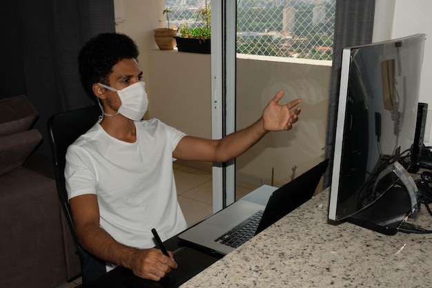 Black man at computer desk wearing pandemic mask