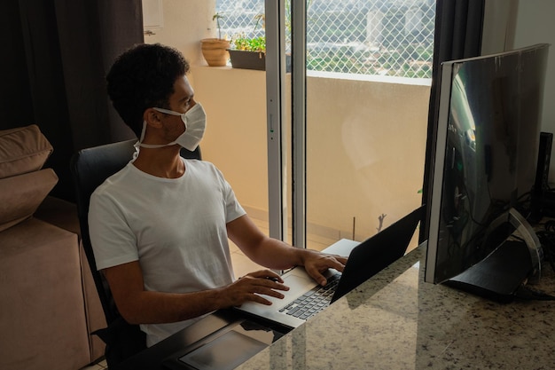 Black man at computer desk wearing pandemic mask