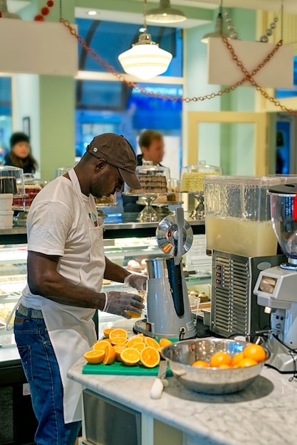 カフェカウンターでオレンジジュースを抽出する黒人男性