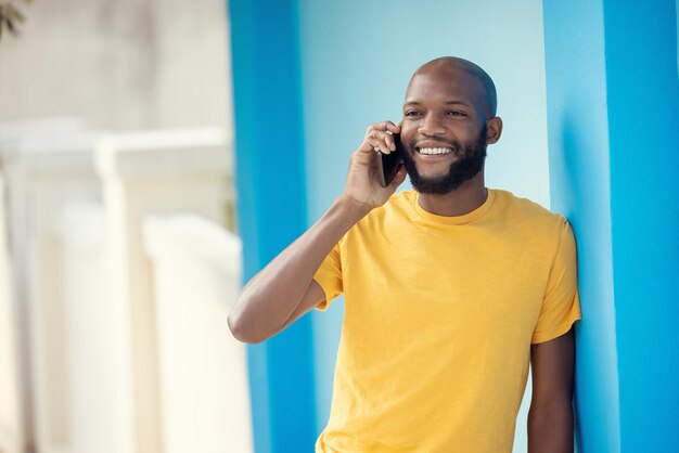 Black man fashion or phone call on blue background or city wall for talking communication or social networking app Smile happy or student on mobile technology in trendy cool or stylish clothes