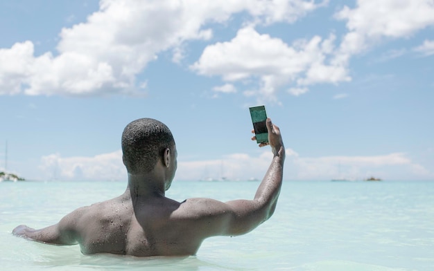 Black man from behind taking selfie in the sea