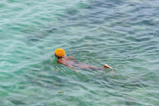 黒人男性がターコイズブルーの海で泳いでいます。