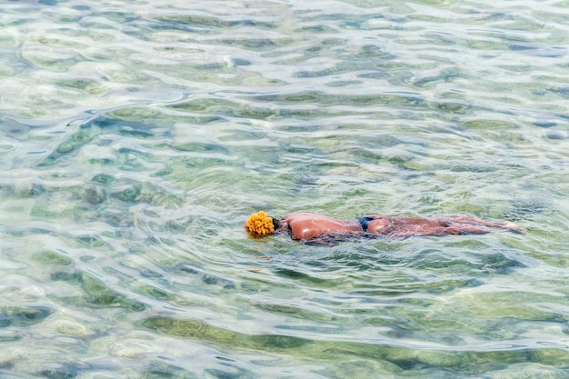 Black man is swiming in the turquoise sea water.