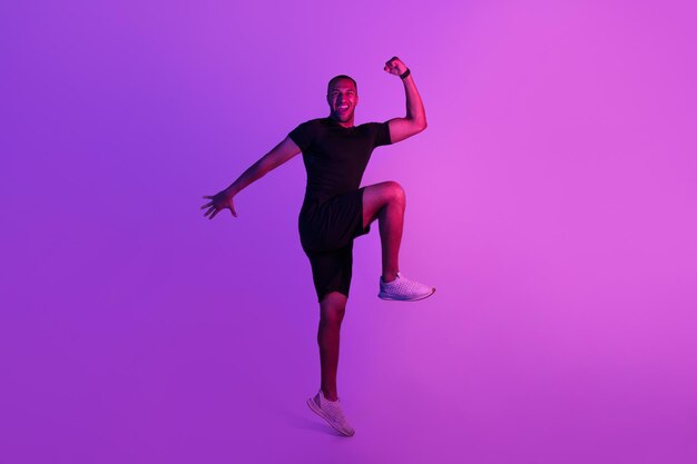 Black man jumping doing elbow to knee crunch purple background