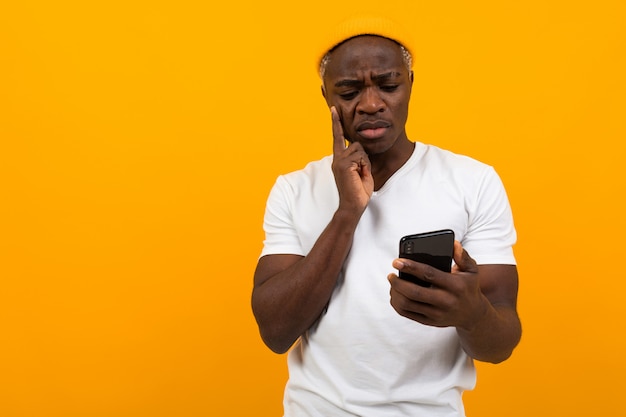 Black man looks in surprise on the phone on orange