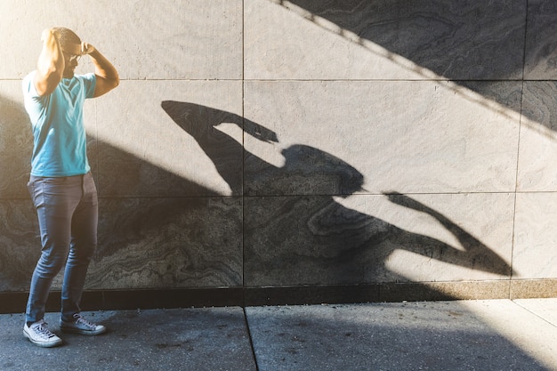 Photo black man playing with his shadow on the wall