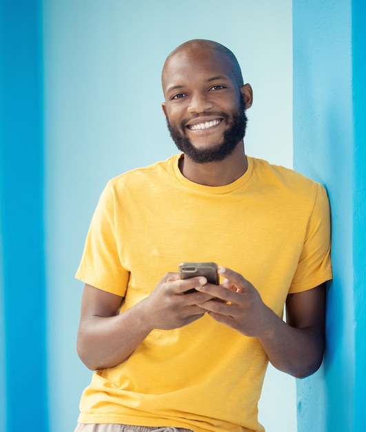 Black man portrait or phone typing on blue background mockup or wall mock up on social media internet app or blogging Smile happy person or fashion clothes on mobile technology for trendy ideas