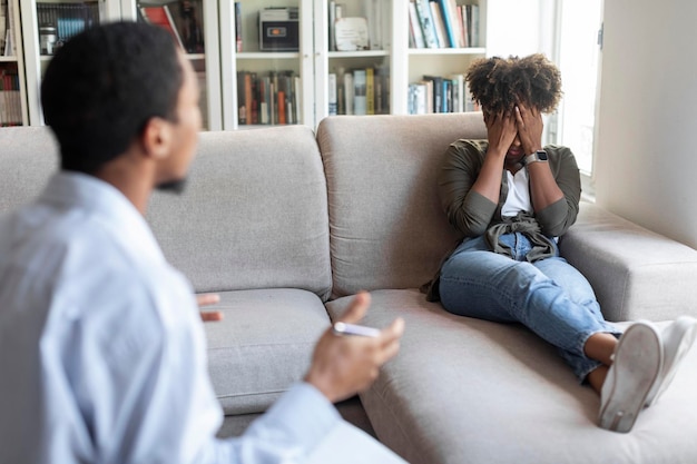 Black man psychologist have conversation with frustrated crying young woman