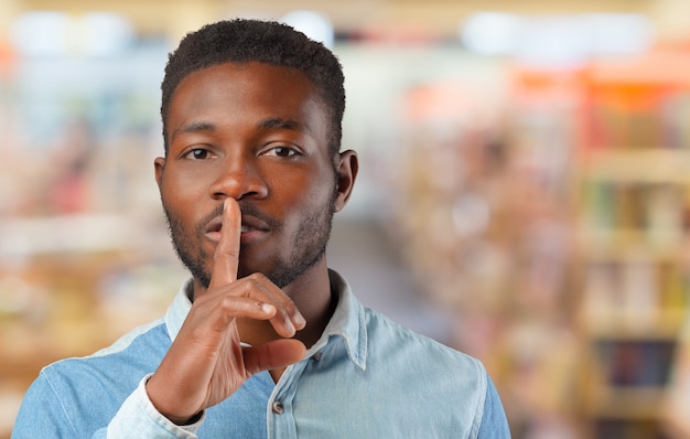 Black man showing silence gesture with finger on his lips