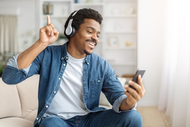 Black man sitting on couch listening to music on phone