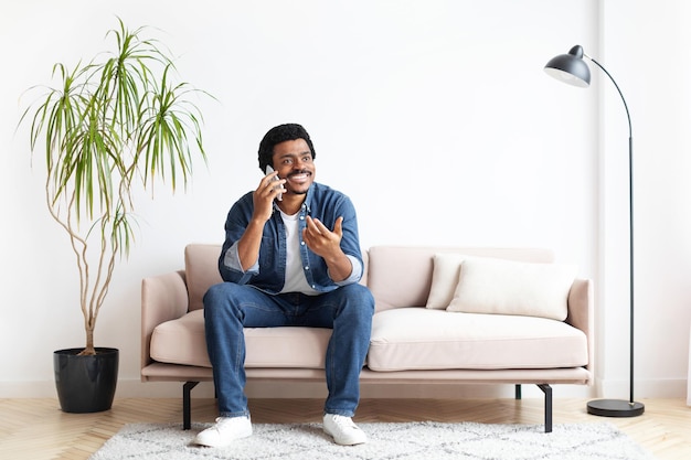 Black man sitting on couch and talking on cell phone