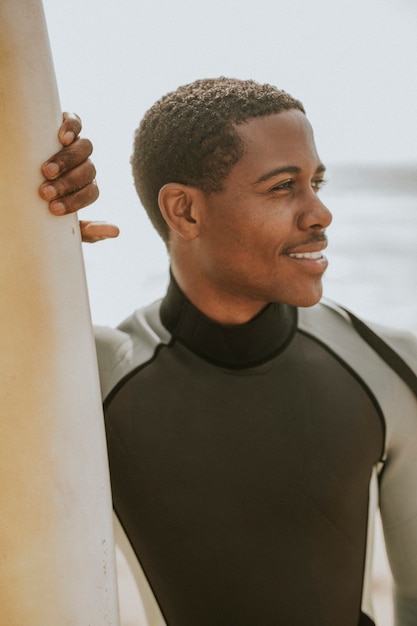 Photo black man standing by the surfboard