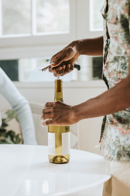 Black man uncorking a white wine bottle