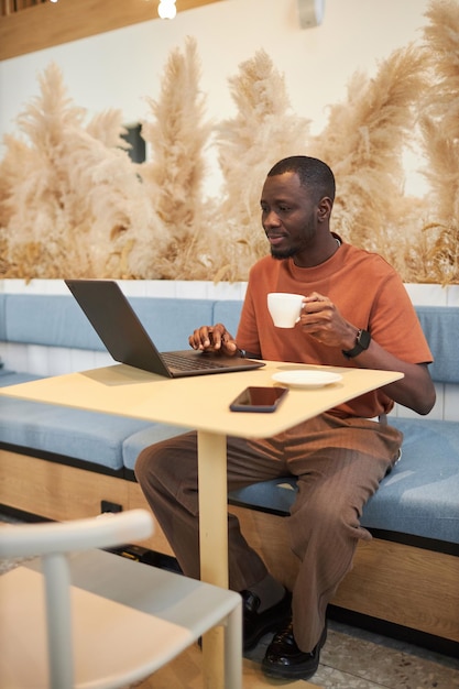 Black man using laptop at table in coffee shop
