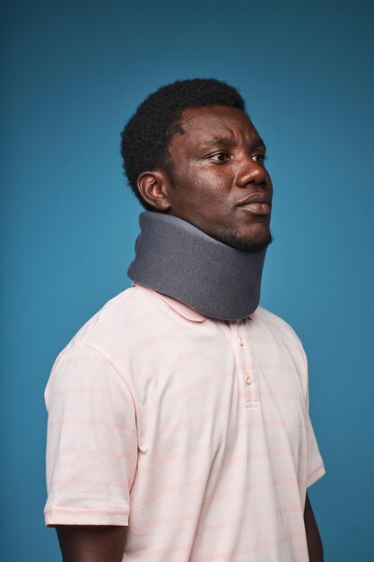 Photo black man wearing neck brace against blue background minimal