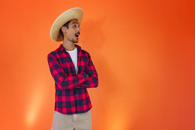 Black Man With Junina Party Outfit Isolated on Orange Background Young man wearing traditional clothes for Festa Junina Brazilian June festival