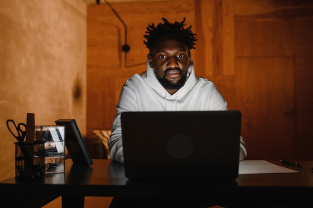 A black man works at a laptop closeup of his face video conferences